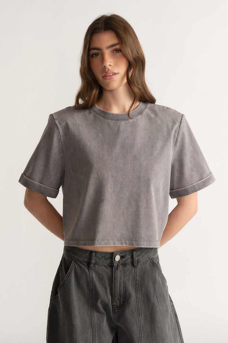 Model wearing a grey shoulder pad tee with dark high rise jeans