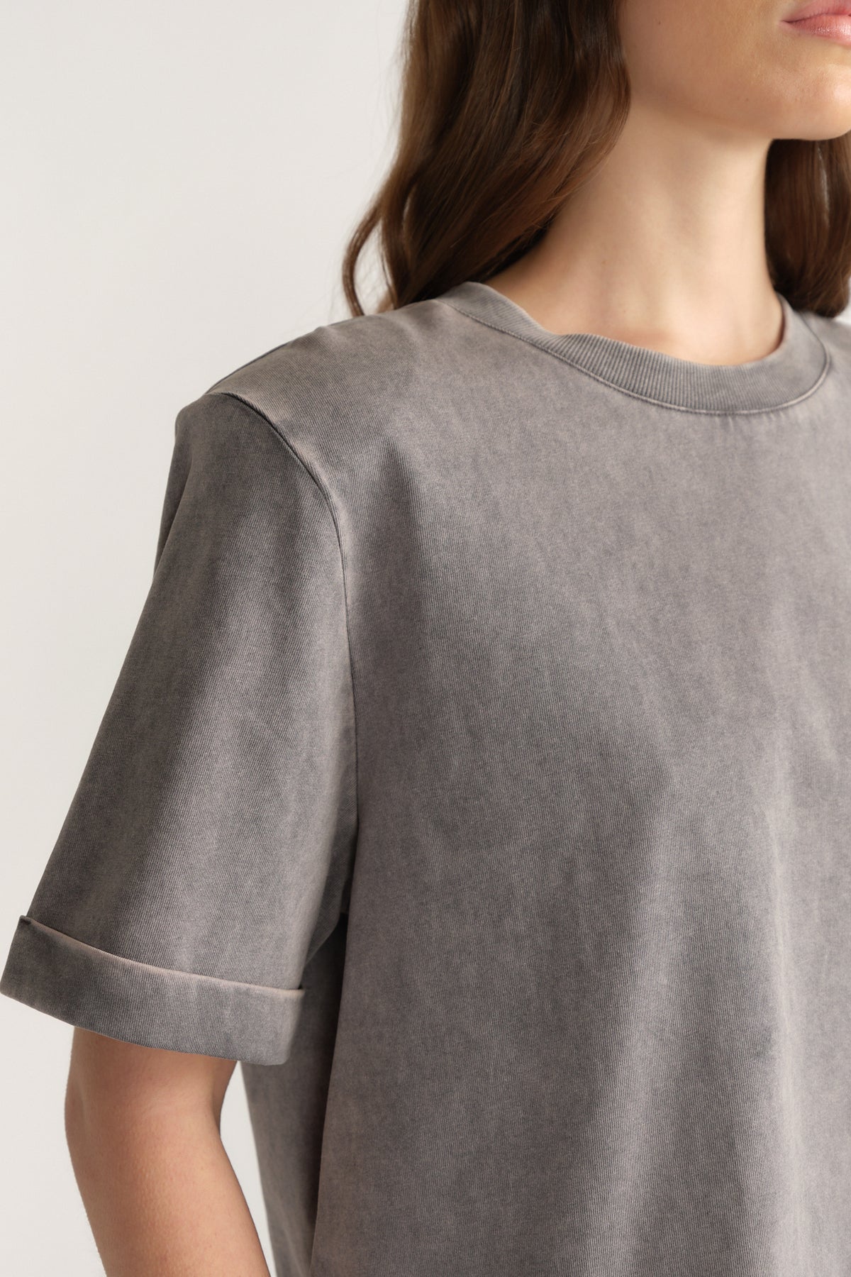 Woman wearing a grey crew neck tee with structured shoulders and rolled sleeve cuffs