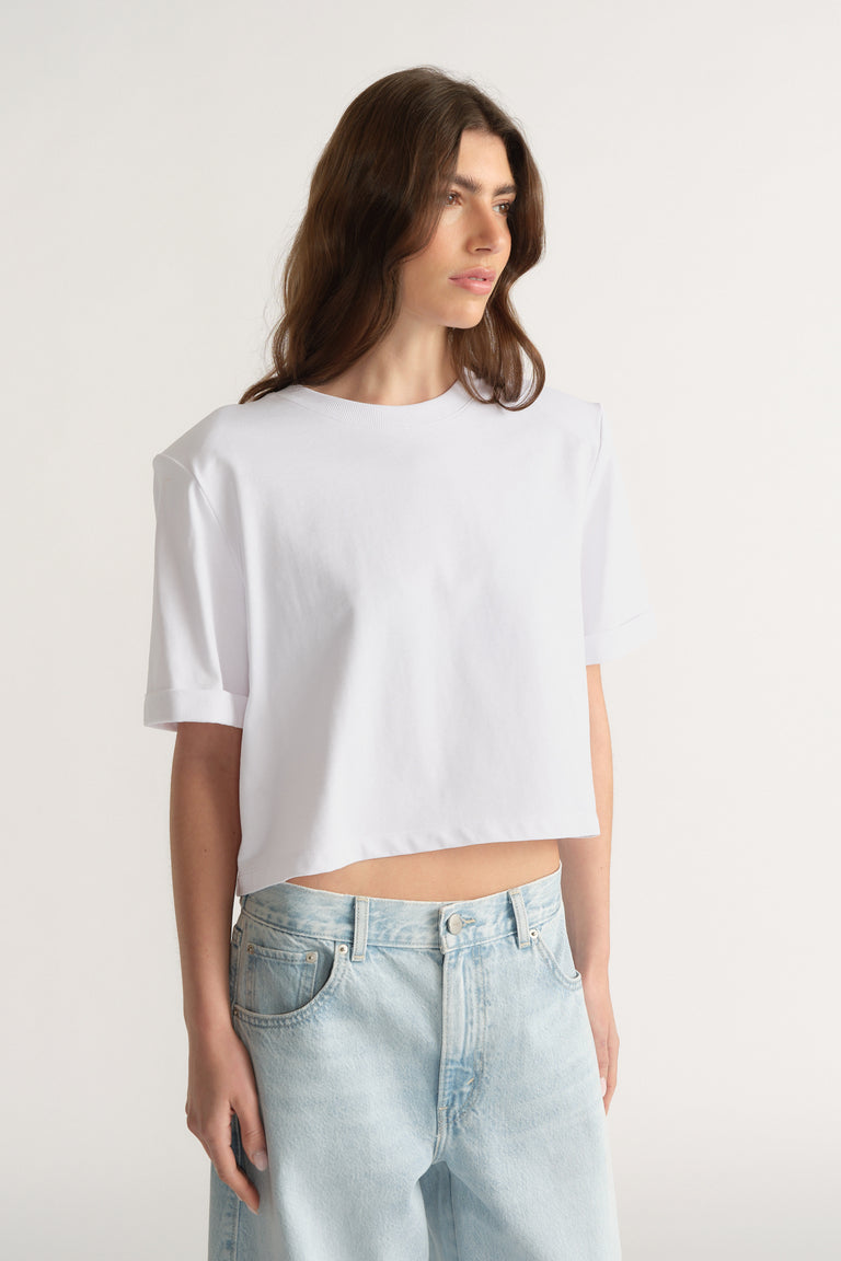Model wearing a white padded shoulder tee with light blue jeans