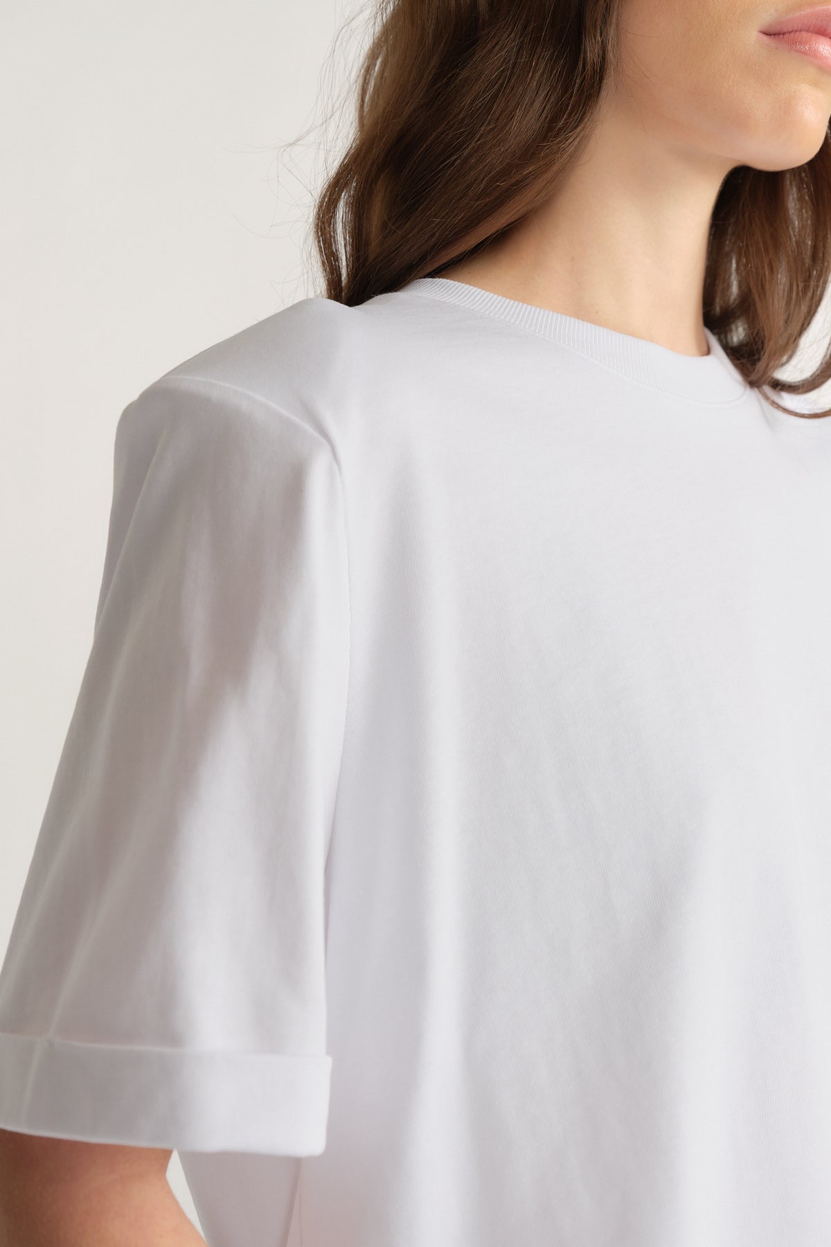 Woman wearing a white crew neck tee with structured padded shoulders and cuffed short sleeves