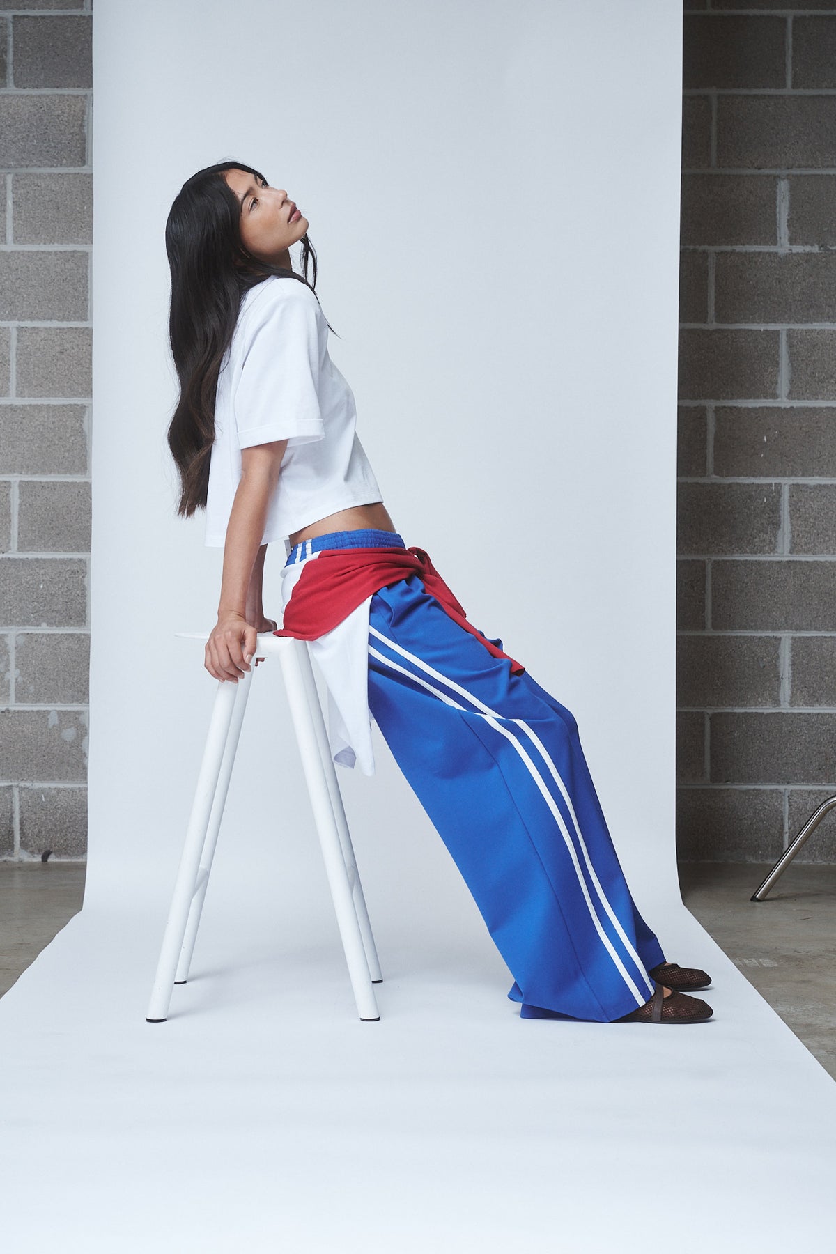 Woman wearing blue wide leg side stripe pants with a white tee and red layer tied at the waist