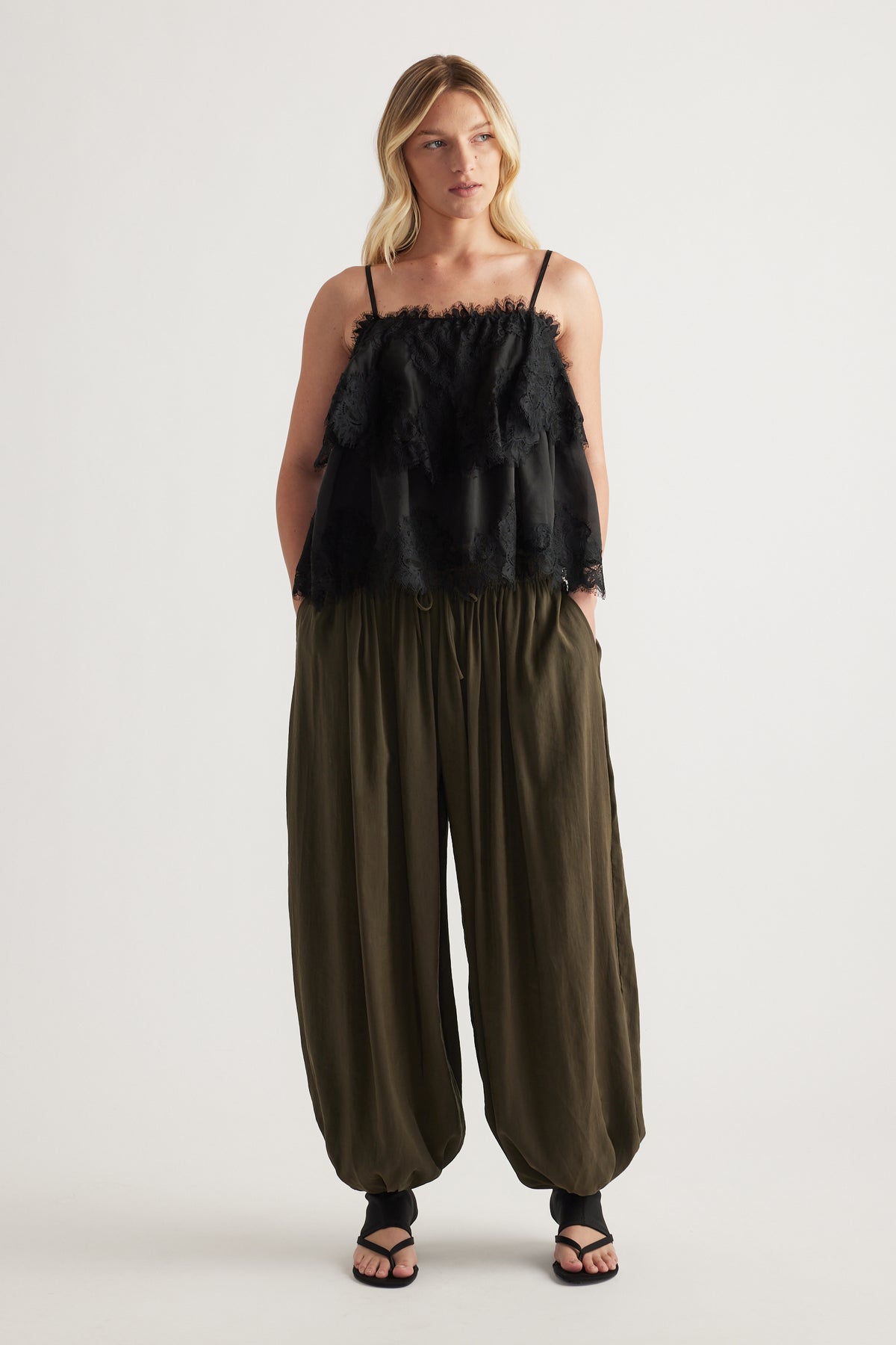 Woman wearing olive balloon leg pants with an elastic drawstring waist and full length fit