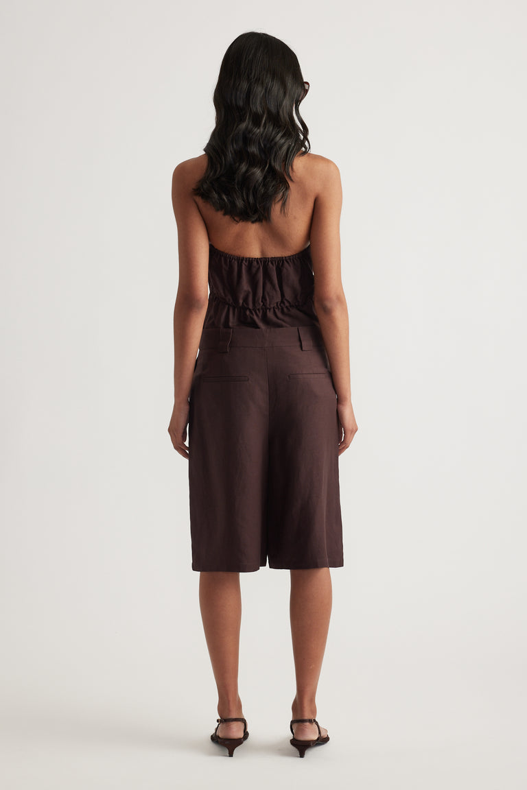 Back view of a woman wearing dark brown linen blend shorts with a matching halter top