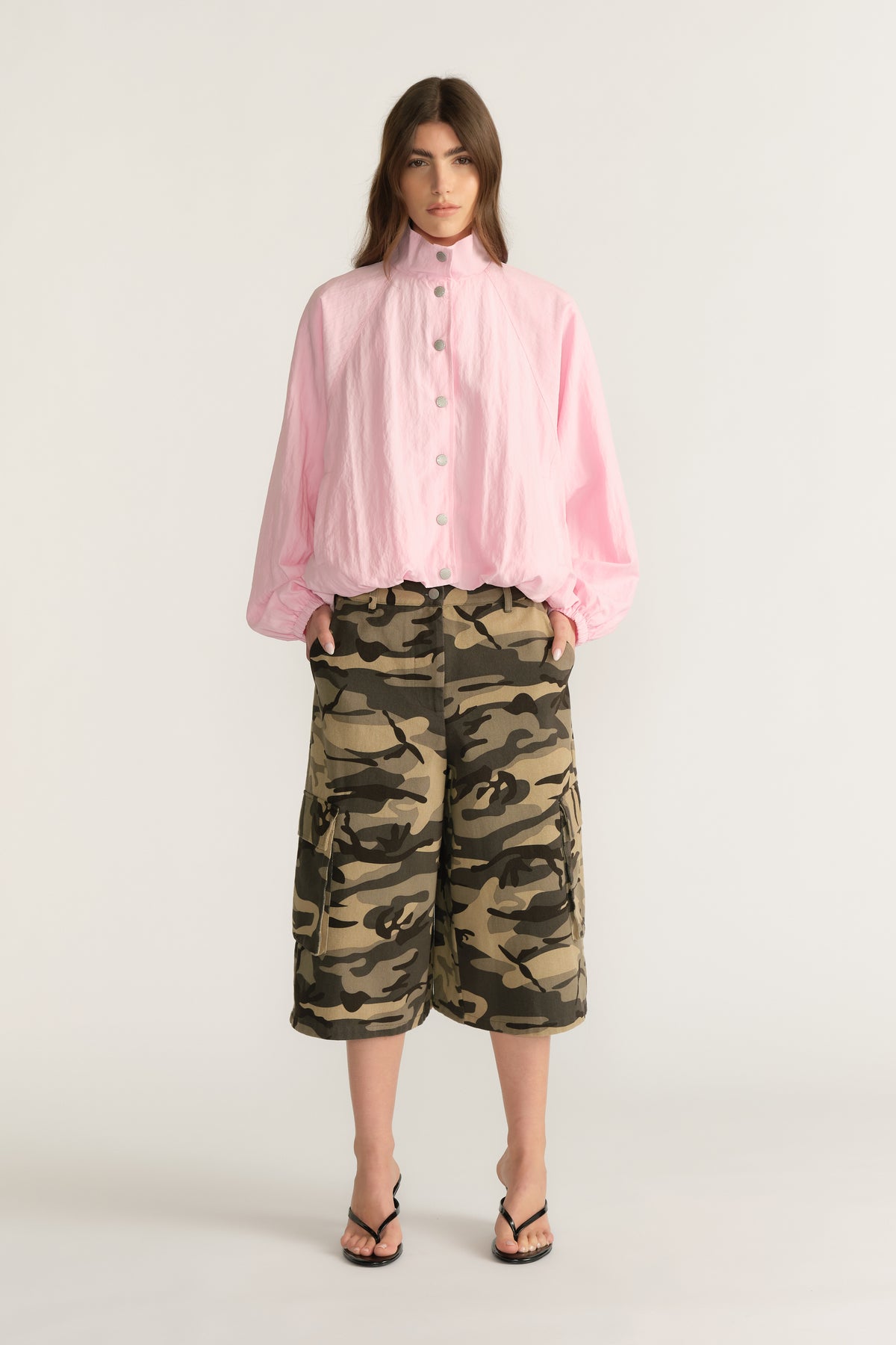 Woman wearing a lightweight pink funnel-neck jacket with camouflage shorts and sandals