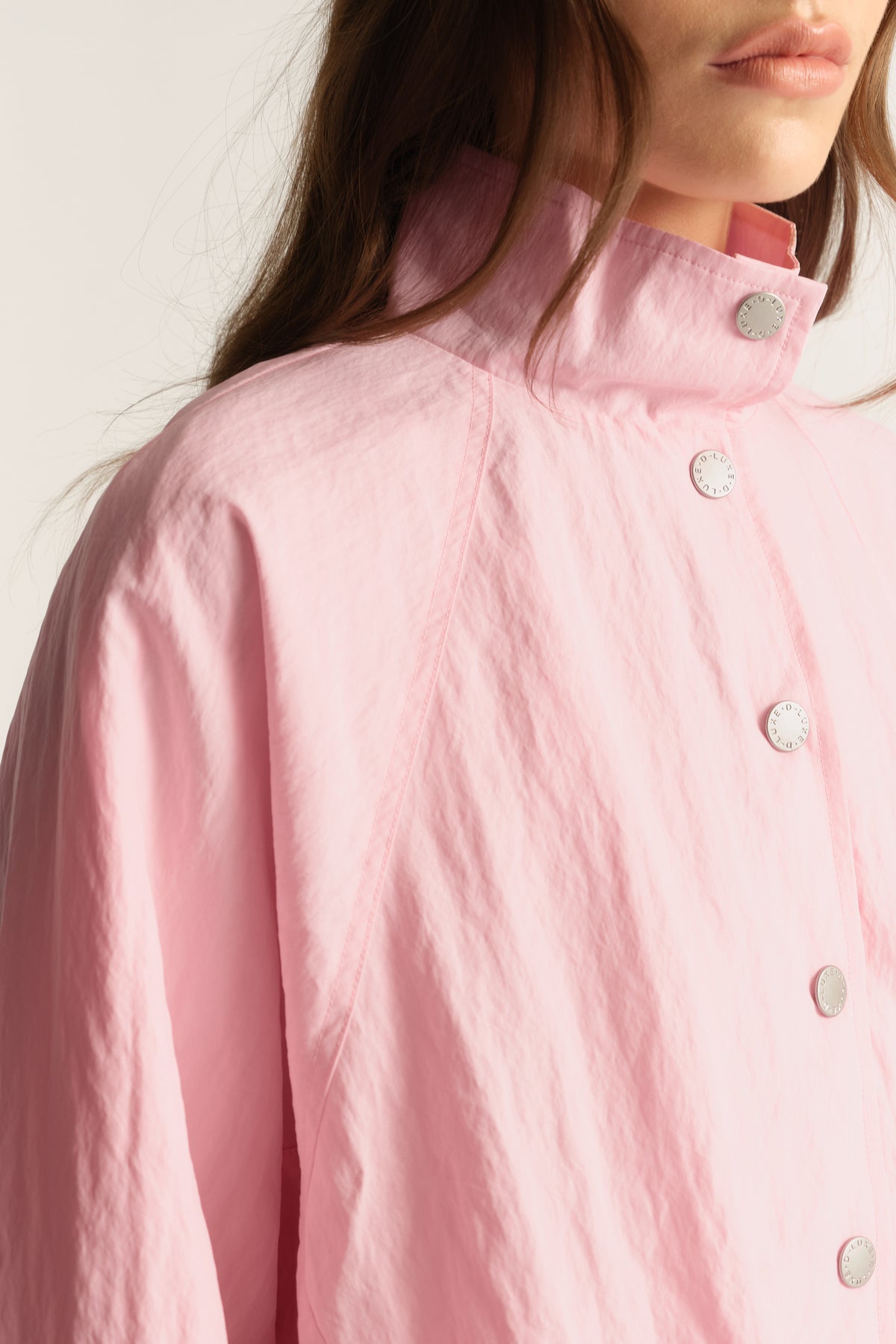 Woman wearing a pink lightweight funnel neck jacket with snap buttons
