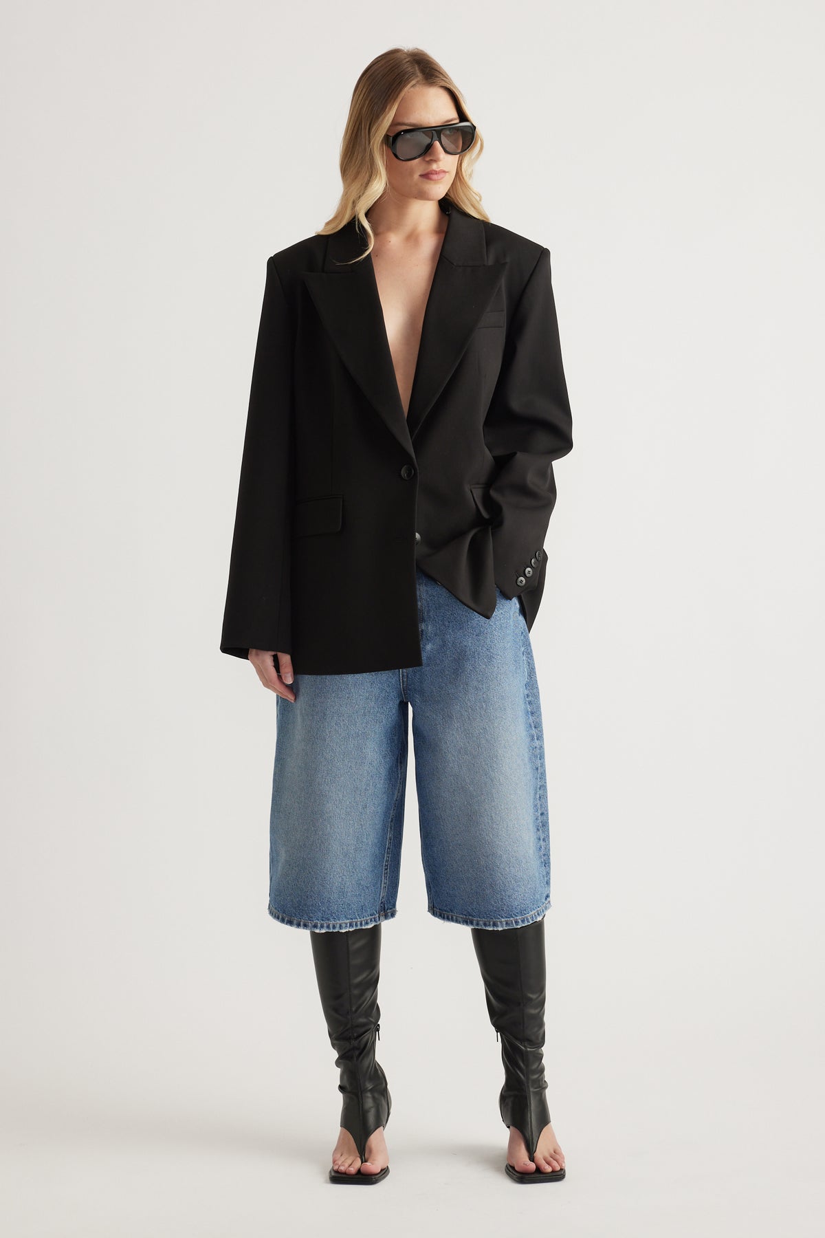 Woman in a black blazer, cropped wide leg jeans and black thong front wedge boots