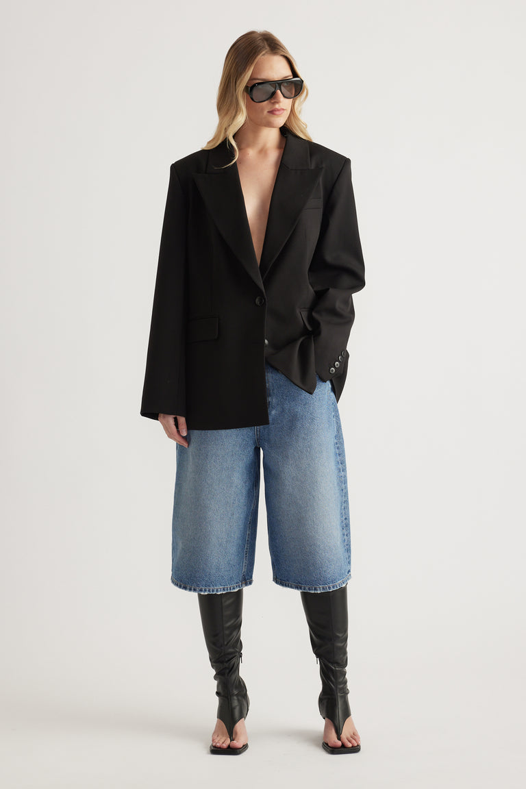 Woman in a black blazer, cropped wide leg jeans and black thong front wedge boots