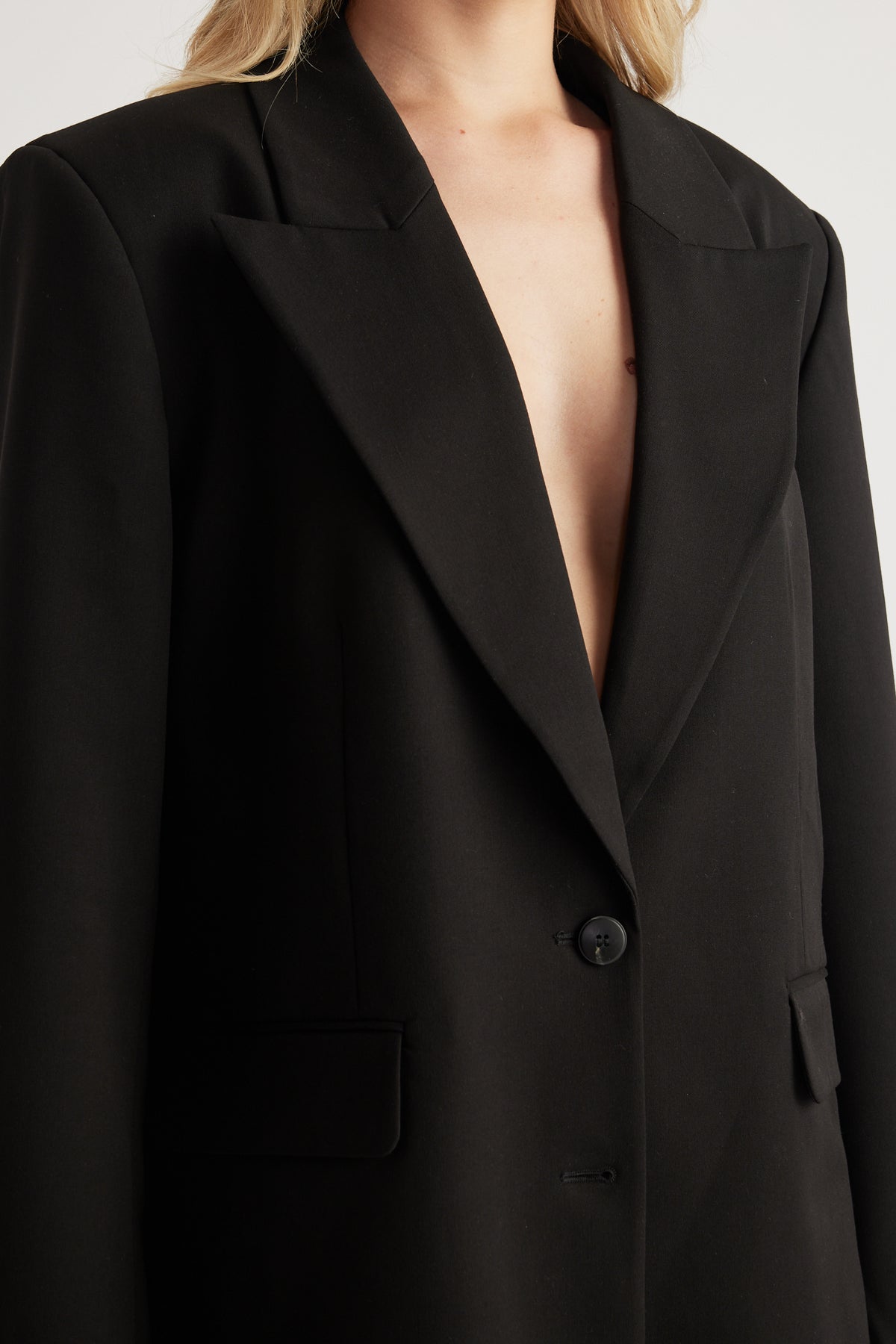 Woman wearing a black oversized blazer with notched lapels button closure and front pockets