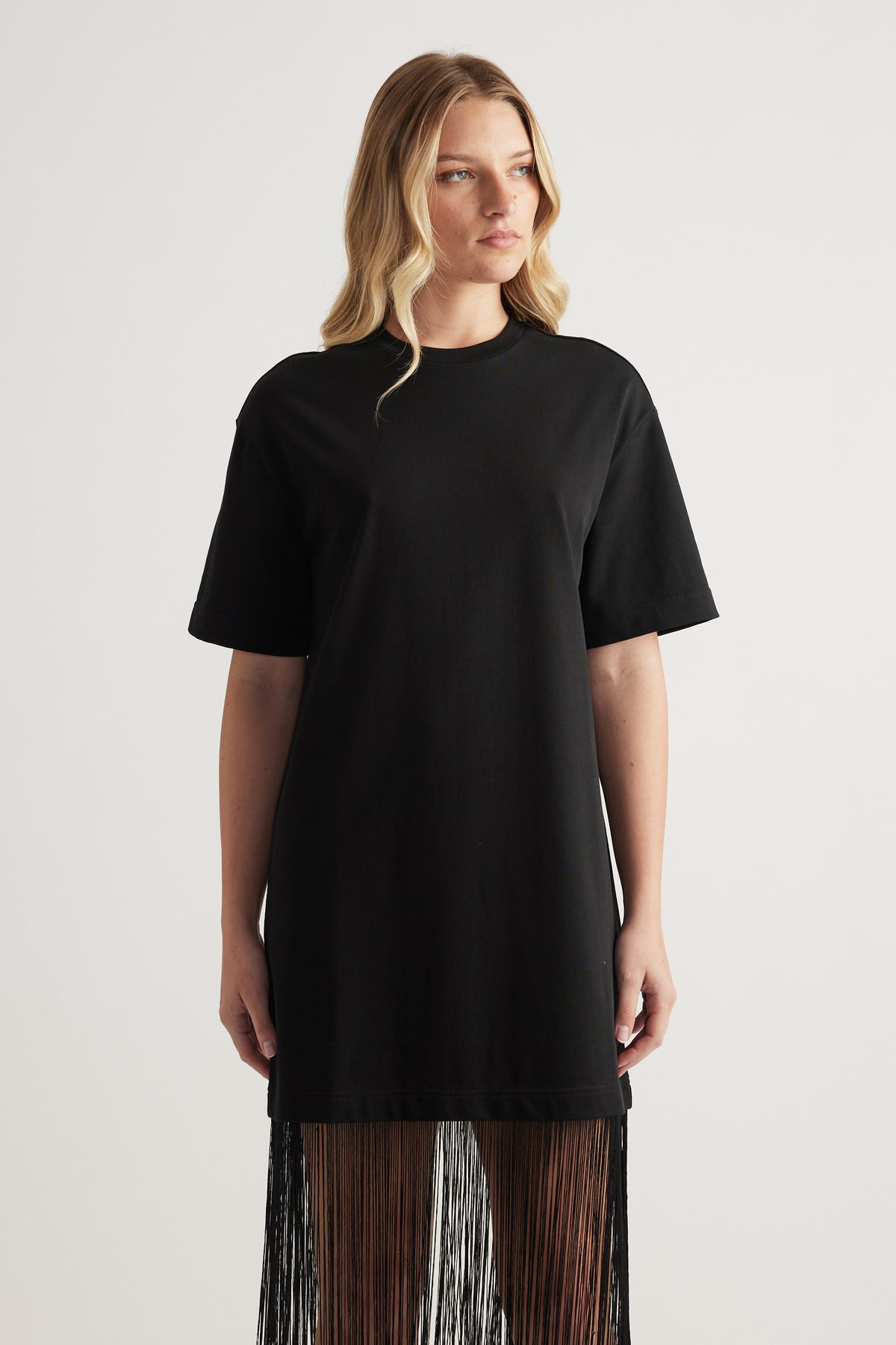 Woman wearing a black short sleeve maxi dress with a crew neck and fringed hem