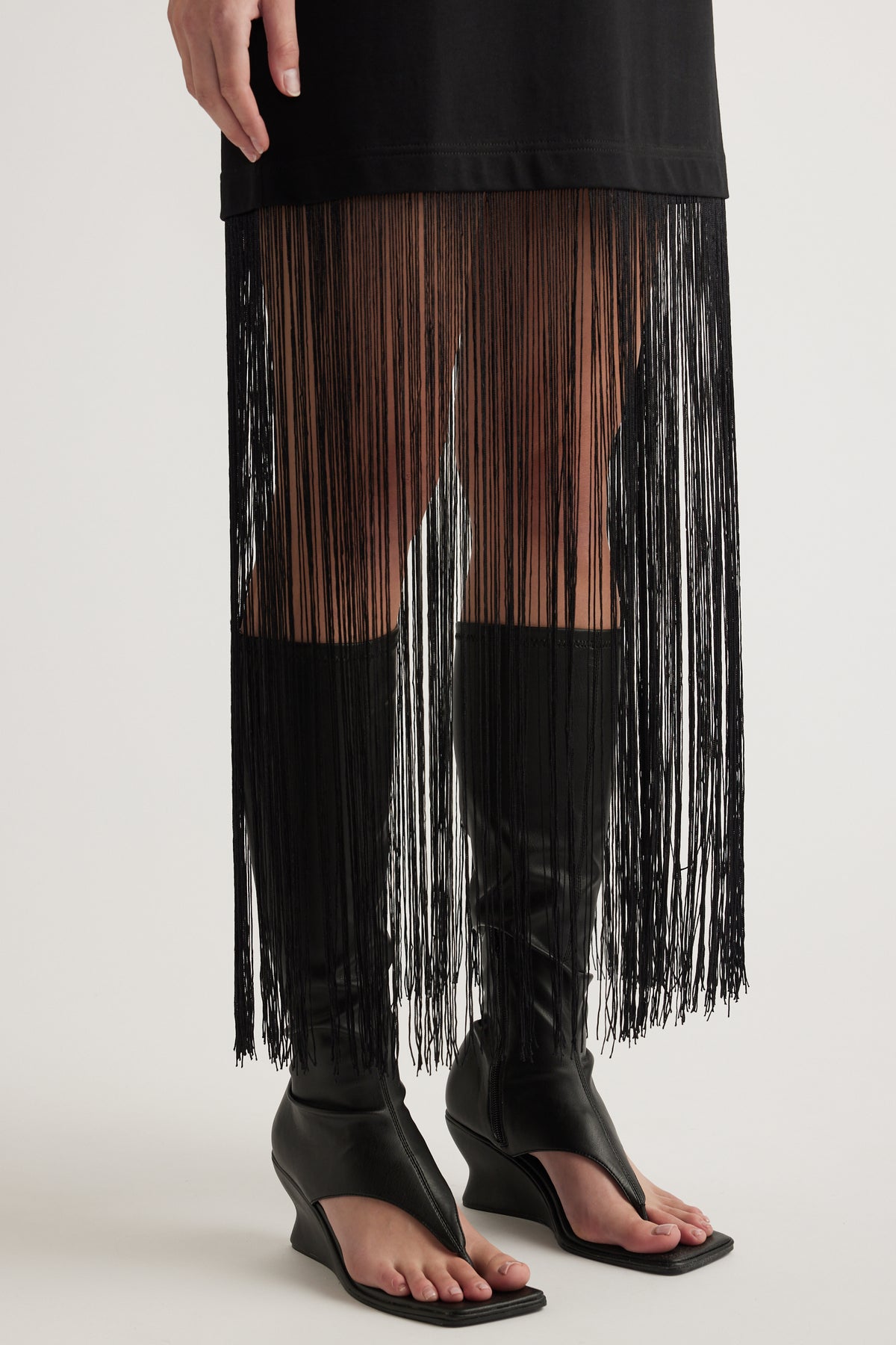 Black maxi dress with long fringe hem styled with black heeled sandals