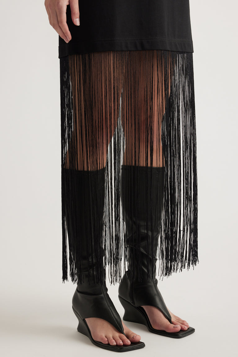 Black maxi dress with long fringe hem styled with black heeled sandals