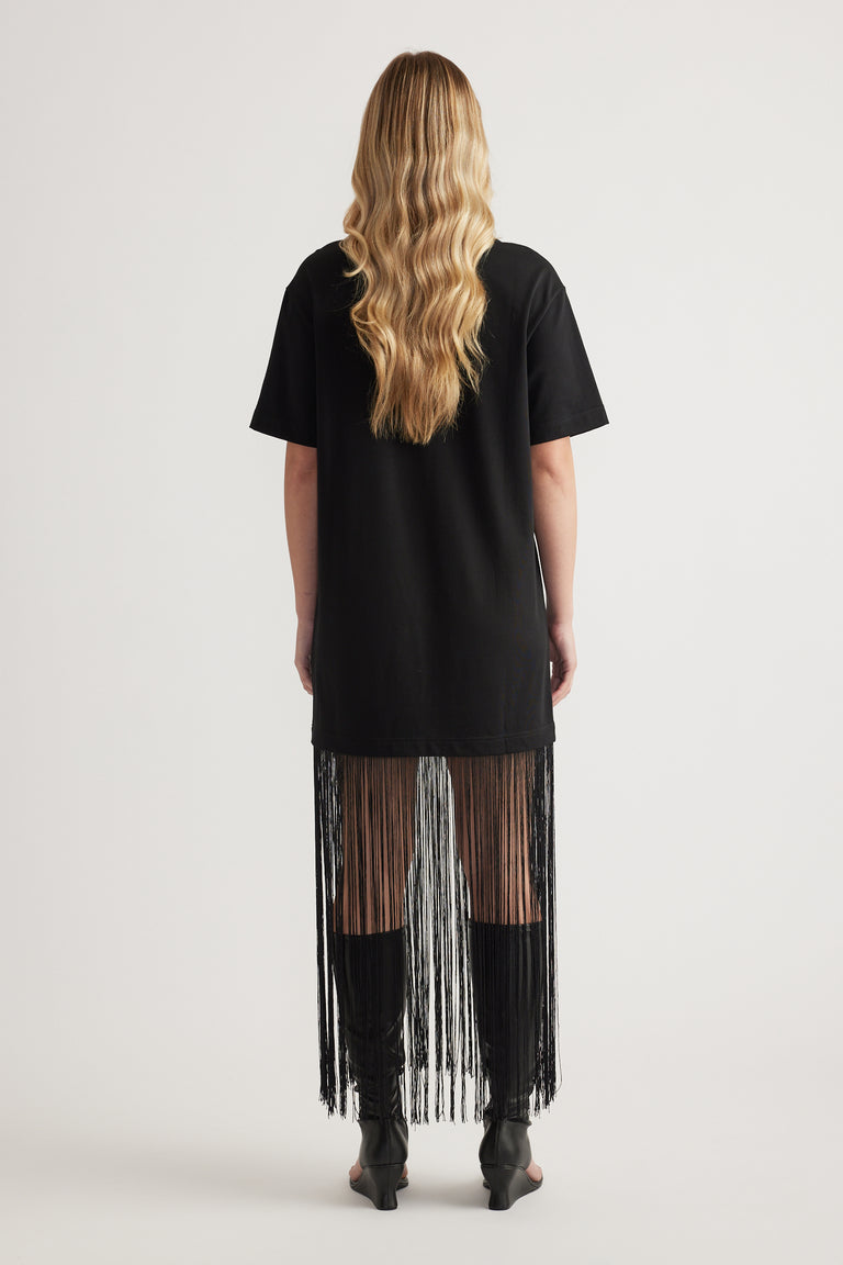 Back view of a woman wearing a black maxi dress with short sleeves and a long fringe hem