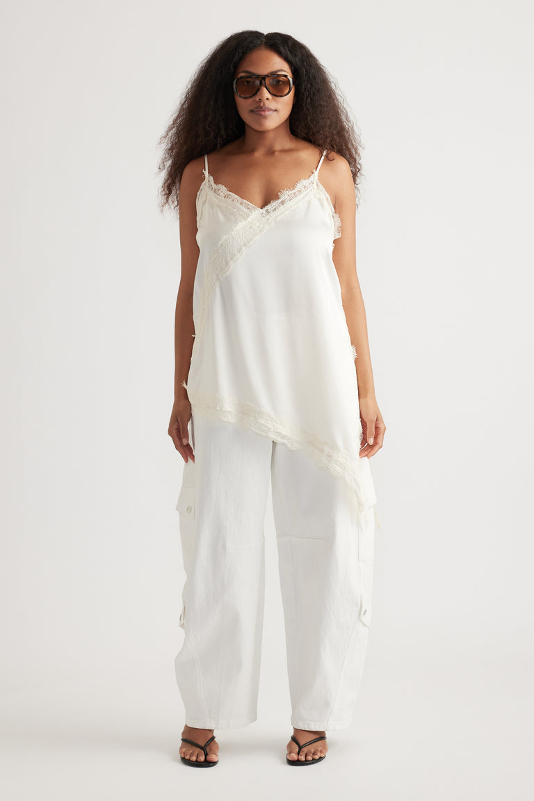 Woman wearing a white lace-trim camisole with relaxed cargo pants, sunglasses and strappy sandals