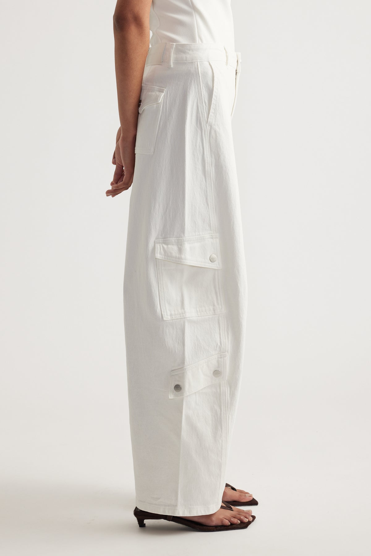 Model wearing white high-rise barrel-leg cargo jeans with multiple utility pockets and a full-length fit