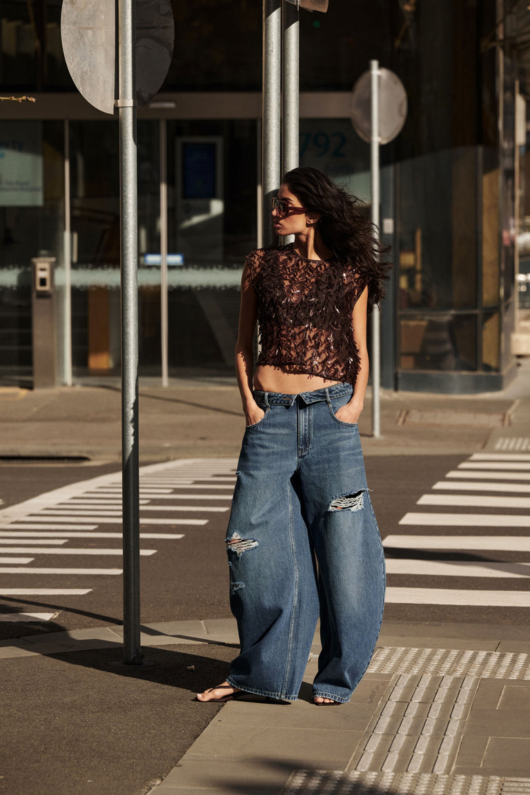 Woman wearing a brown textured cropped top and relaxed wide leg ripped jeans