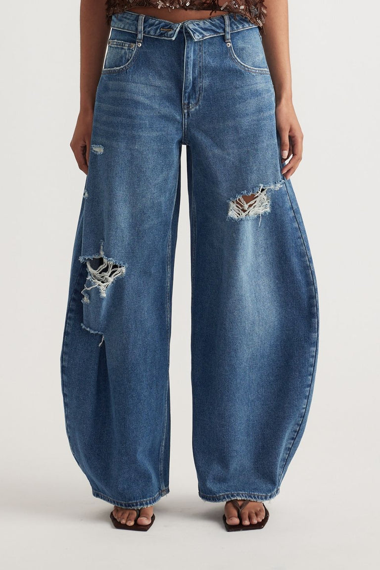 Woman wearing relaxed blue barrel leg jeans with distressed rips and a fold over waistband