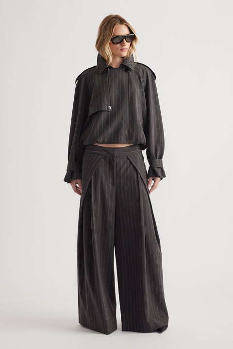 Woman wearing oversized pinstripe blazer with button detail and matching wide-leg pants paired with black sunglasses
