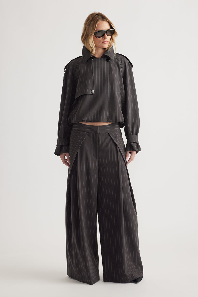 Woman wearing oversized pinstripe blazer with button detail and matching wide-leg pants paired with black sunglasses