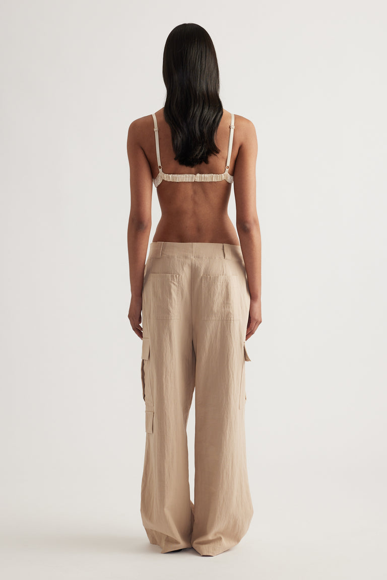 Back view of a model wearing a sequin bralette with adjustable straps and wide leg beige pants