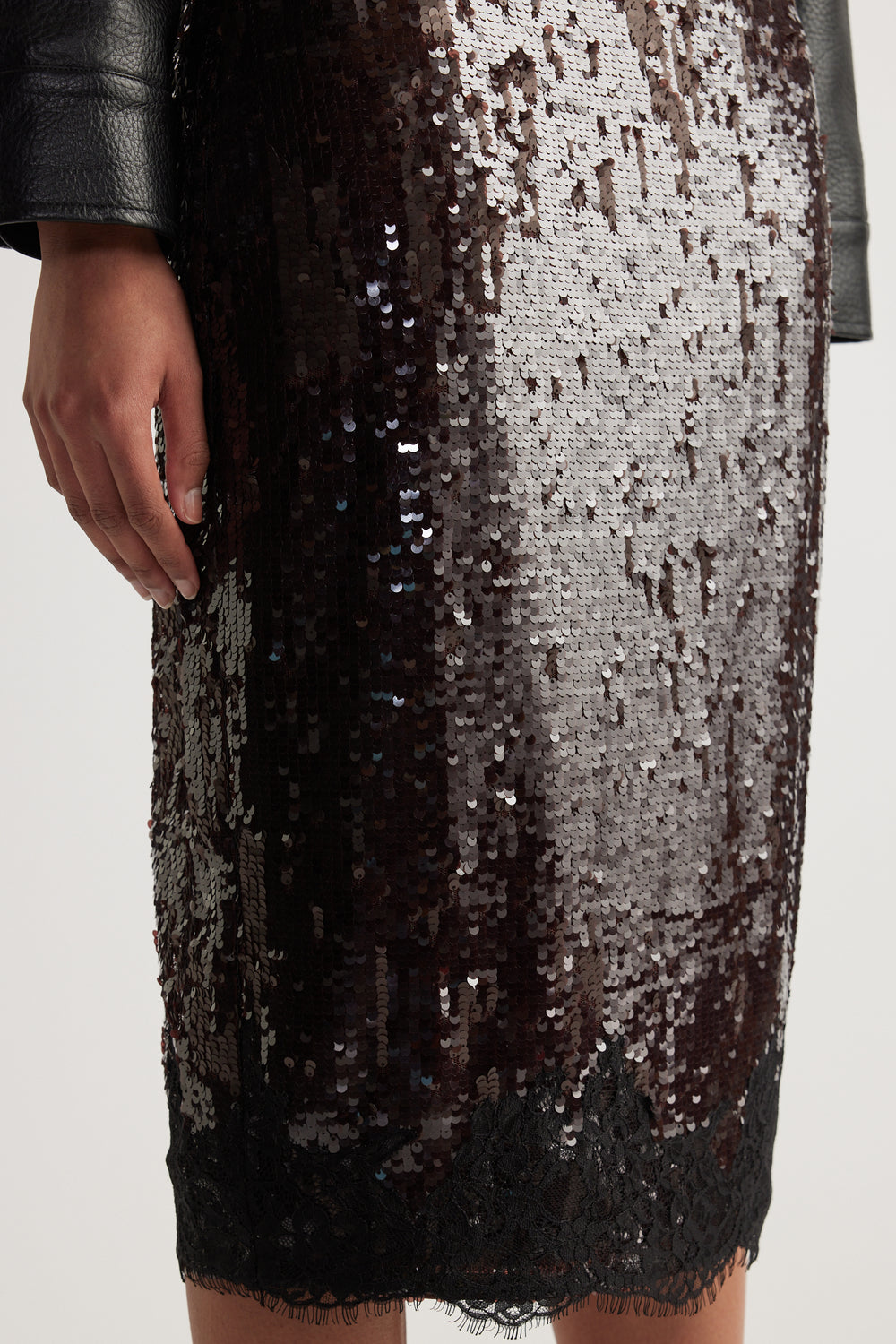 Close-up of a woman wearing a black and silver sequin knee-length skirt with a lace hem
