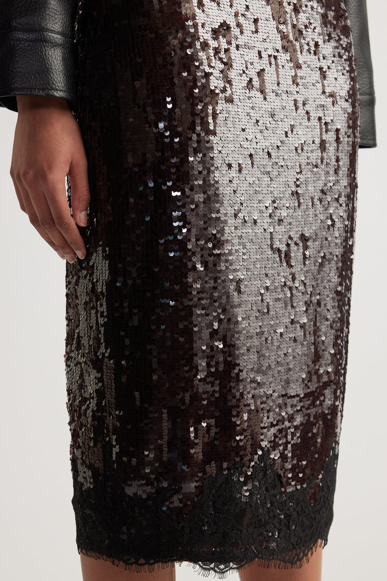 Close-up of a woman wearing a black and silver sequin knee-length skirt with a lace hem