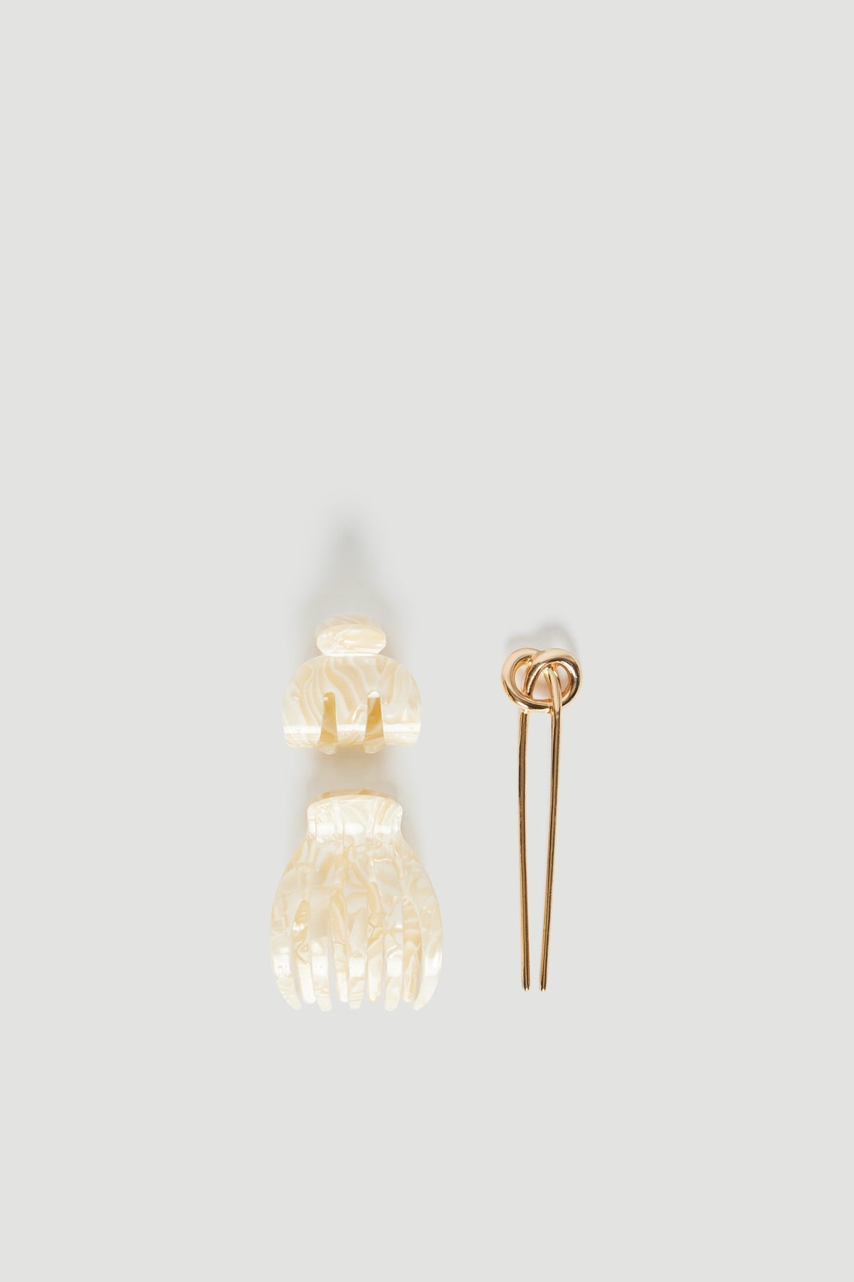 Three-piece hair accessory set with two translucent cream claw clips and a brown hair tie