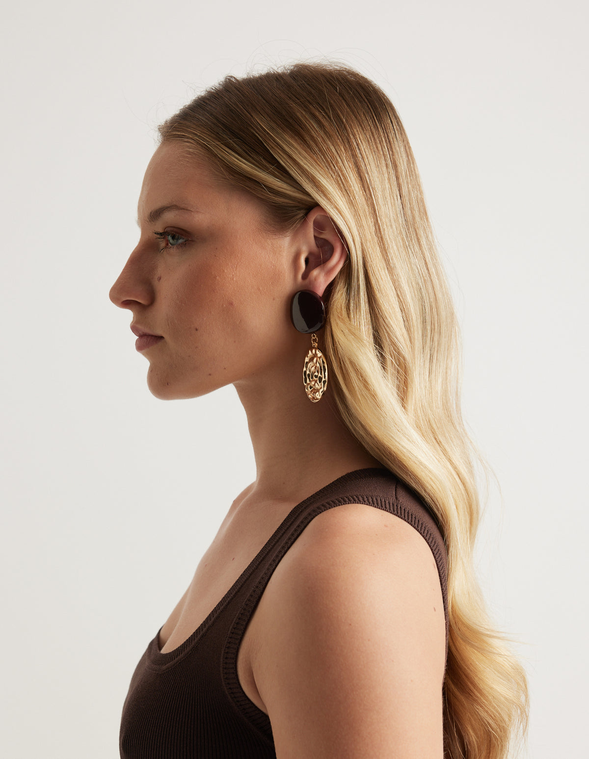 Side profile of a woman wearing a chocolate bead and gold shell drop earring