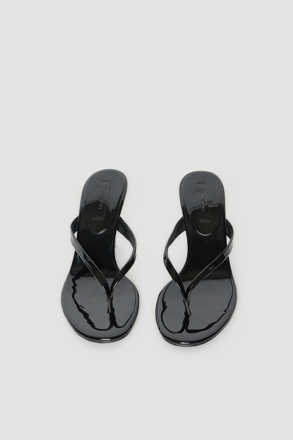 Pair of glossy black thong heels with thin straps and padded footbeds
