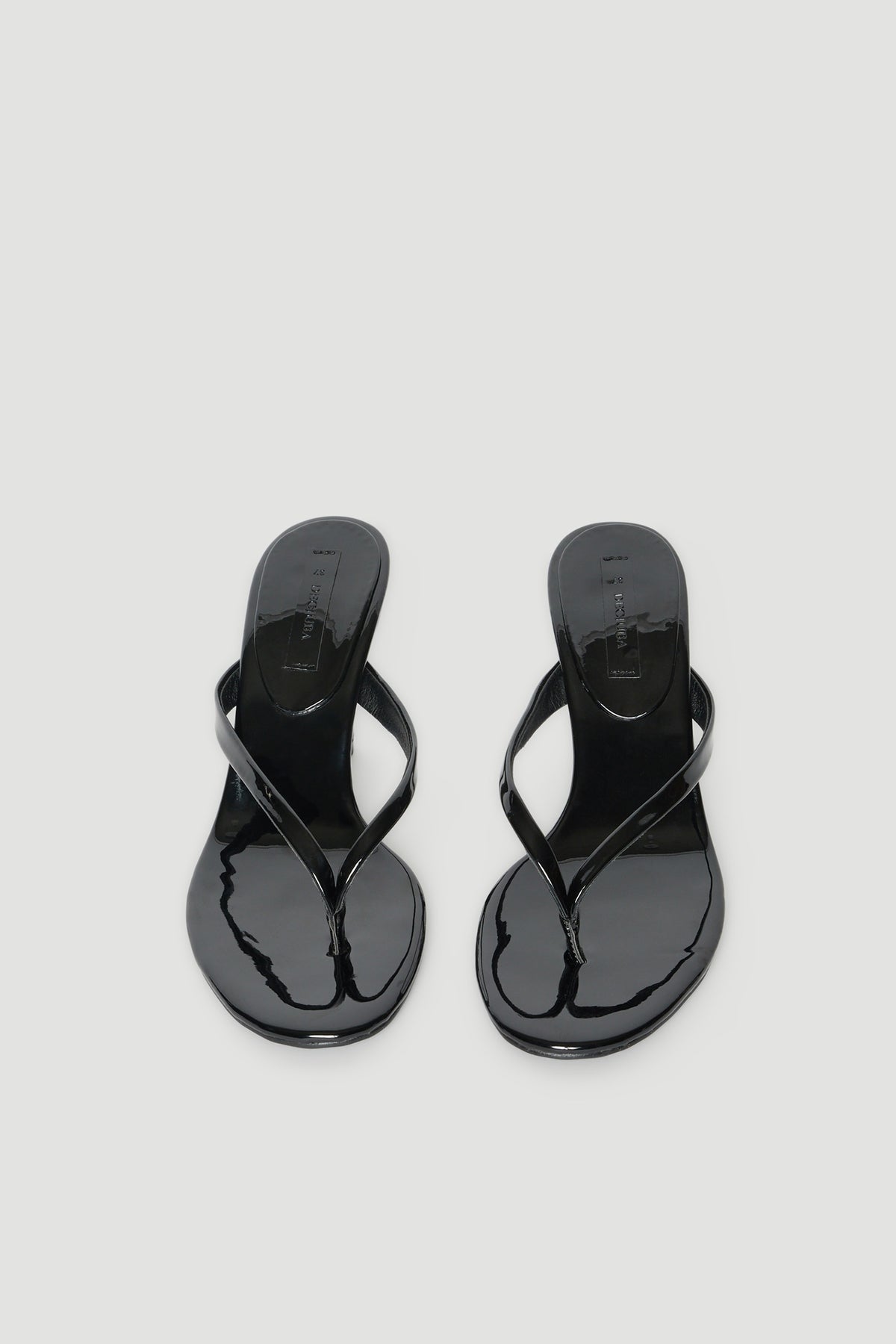 Pair of glossy black thong heels with thin straps and padded footbeds