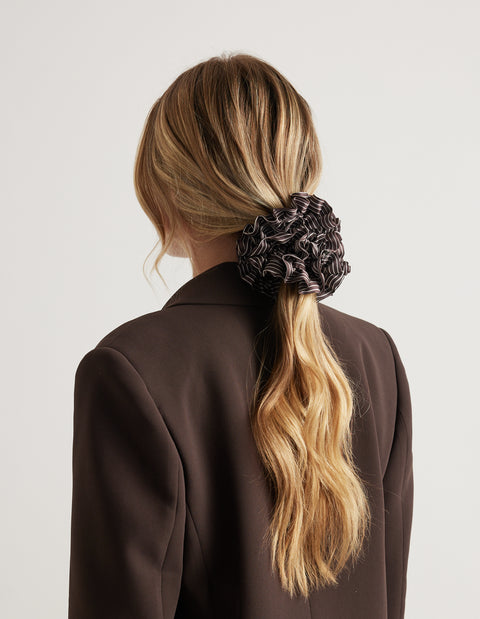 Large tiered ruffled scrunchie securing a woman's long wavy ponytail