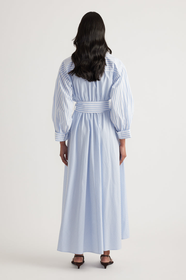Back view of a woman wearing a blue and white striped long sleeve maxi shirt dress with an adjustable belt