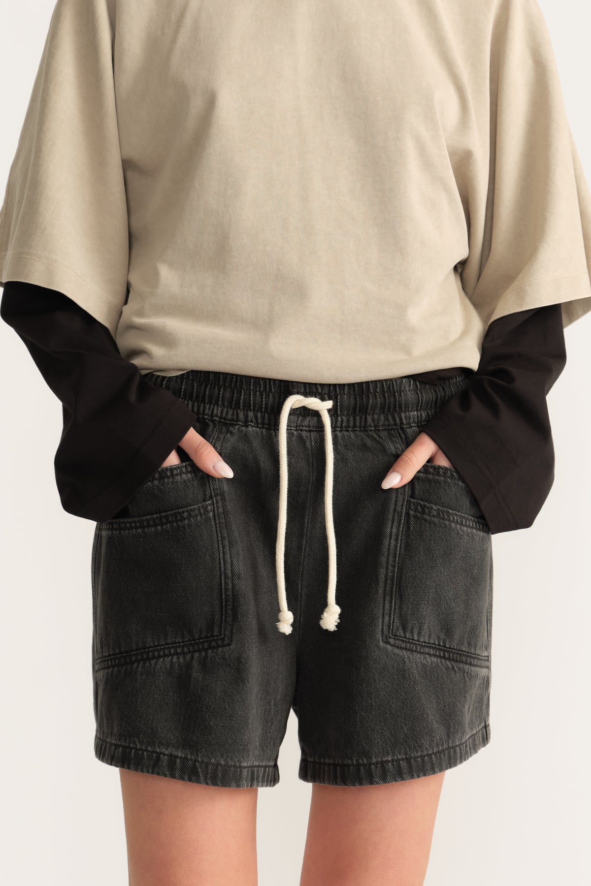Woman wearing black denim pull on shorts with an elastic waist and front pockets
