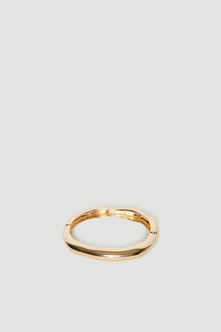 Shiny gold hinge bangle with an uneven textured finish and oval shape