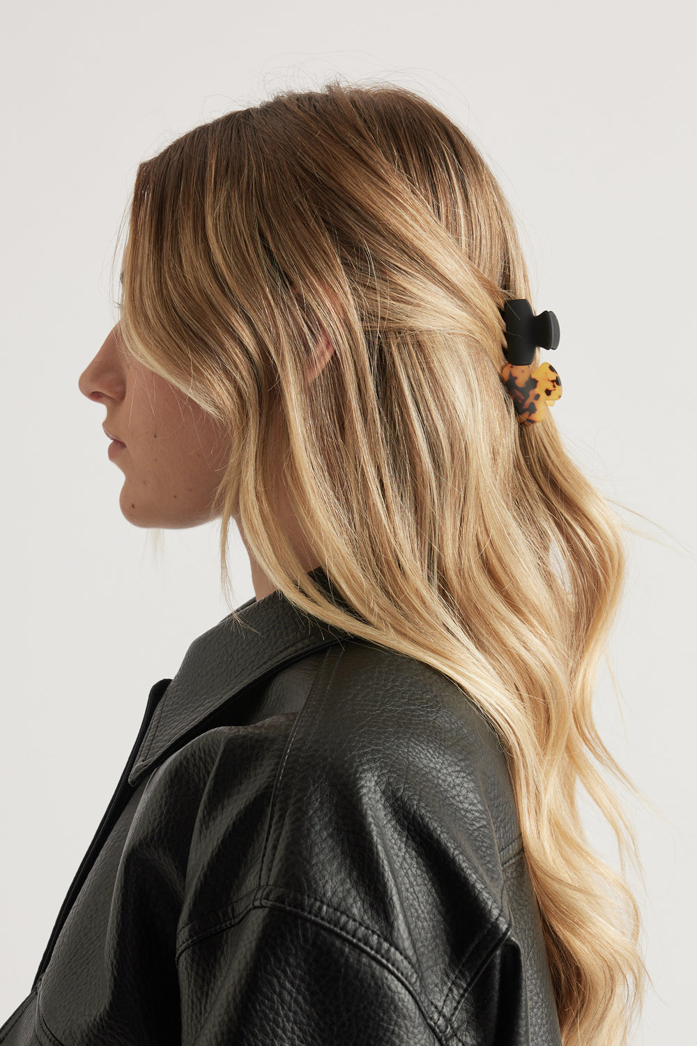 Side profile of a woman wearing an abstract hair claw in her wavy hair