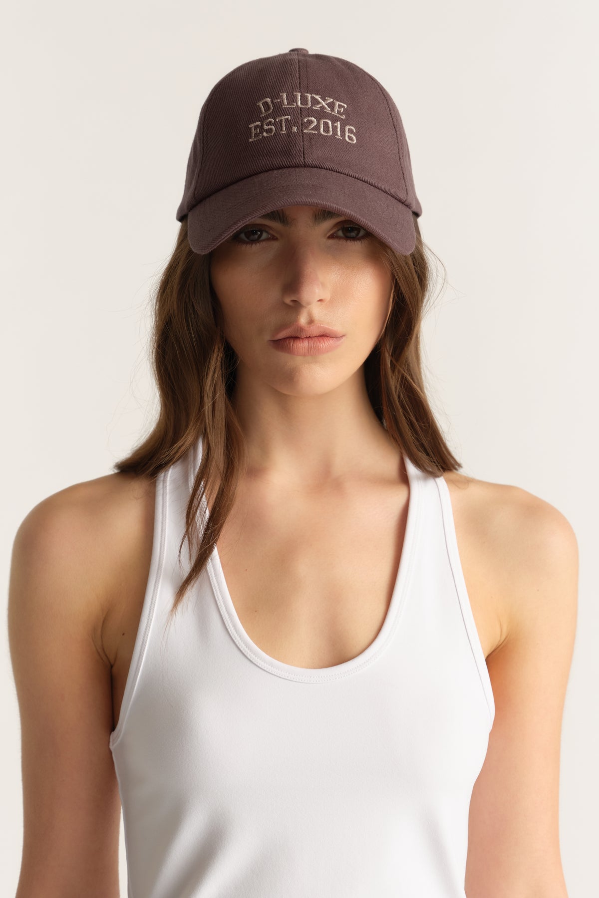 Woman wearing a brown D-Luxe embroidered baseball cap with a white tank top
