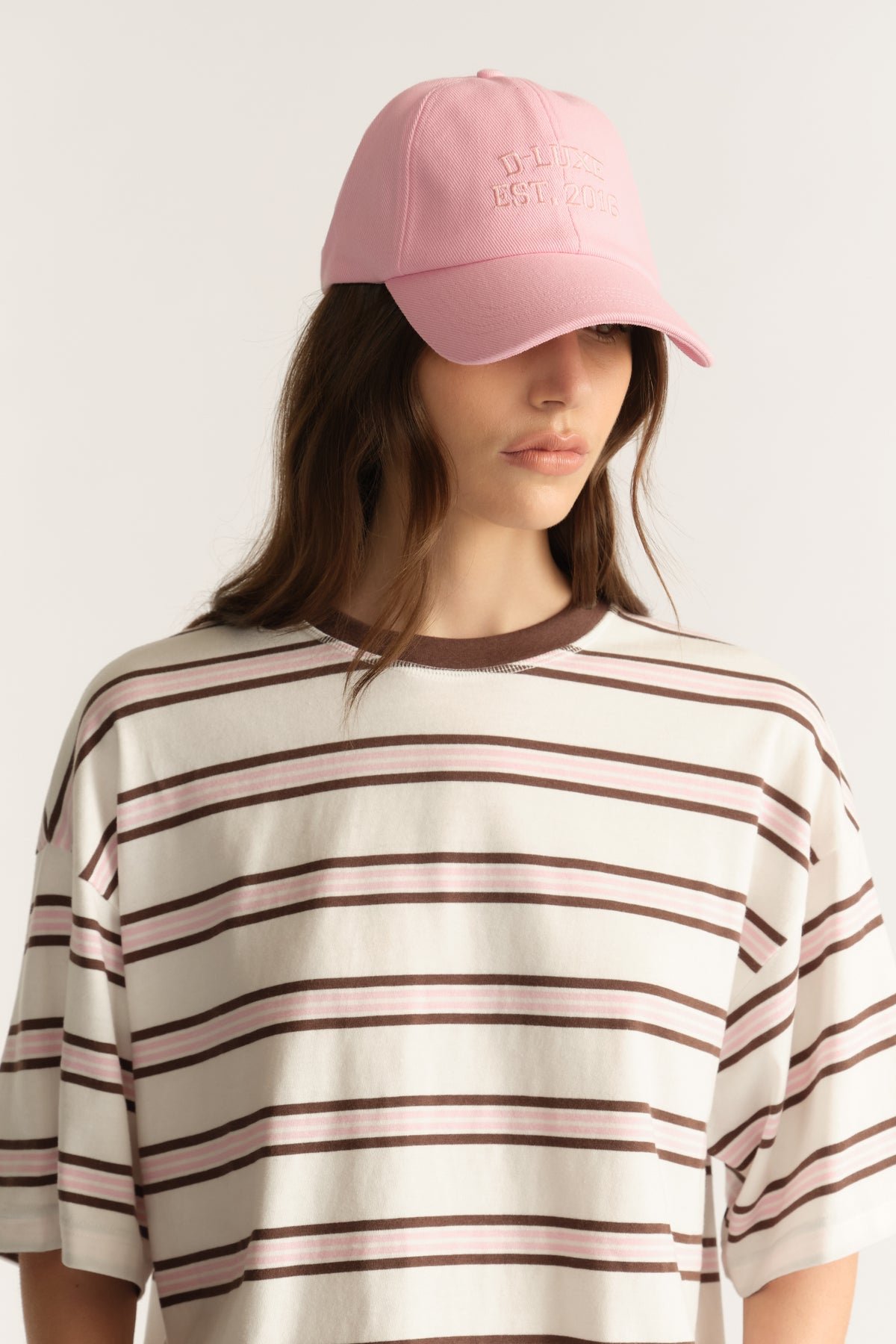 Woman wearing a pink baseball cap with an embroidered logo and curved brim