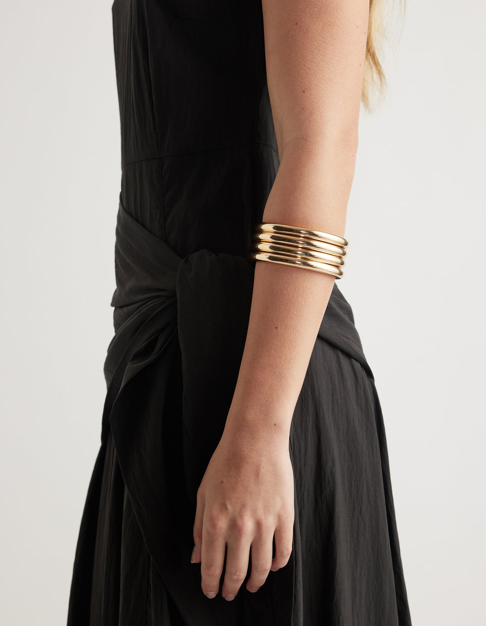 Close-up of stacked gold bangles worn with a black outfit