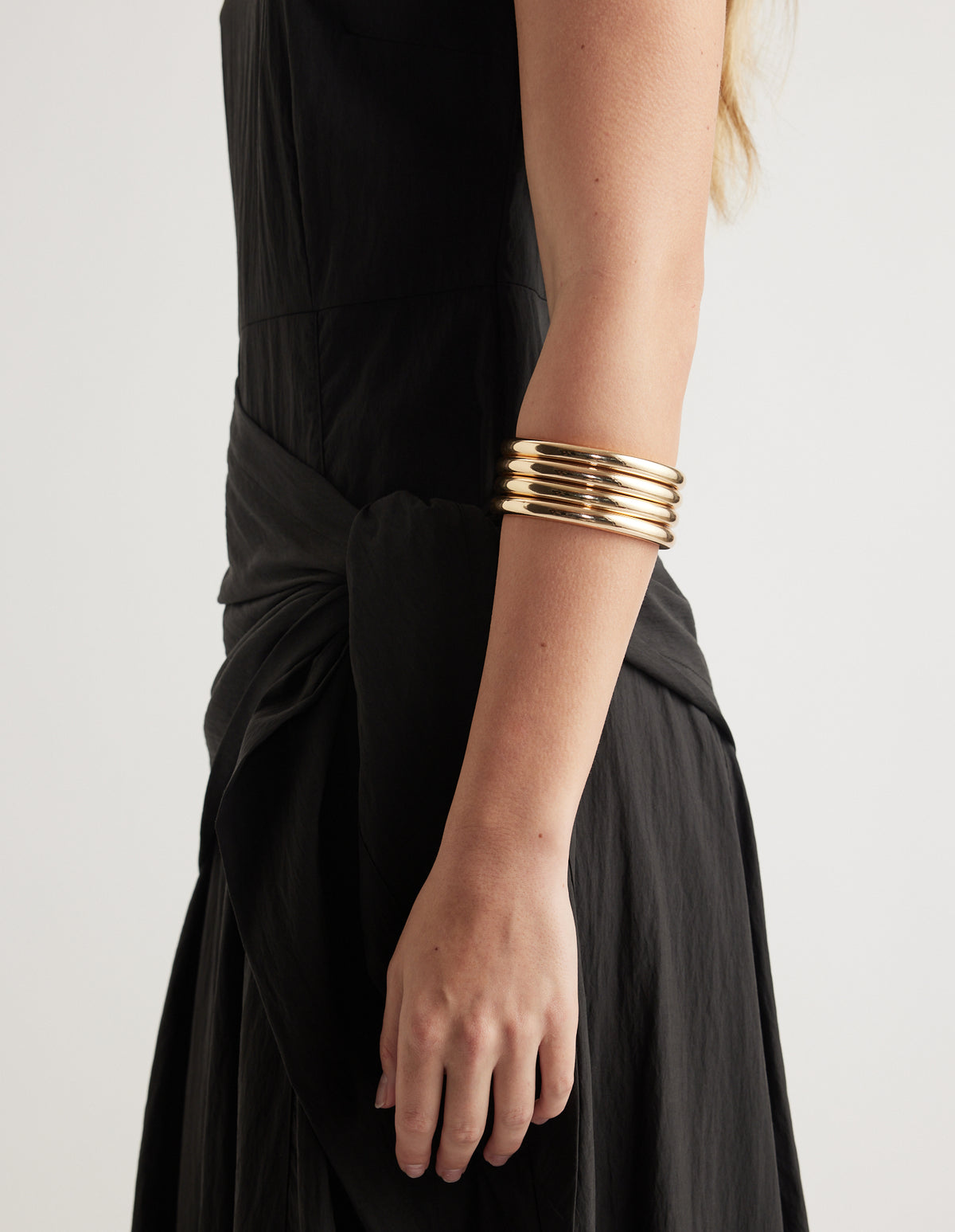 Close-up of stacked gold bangles worn with a black outfit