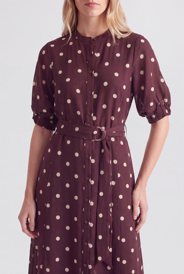 Woman wearing a burgundy polka dot midi dress with puff sleeves and a belted waist