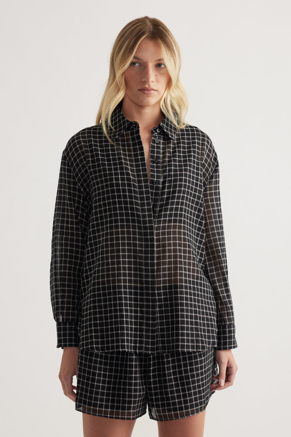 Model wearing an oversized black checked shirt with long sleeves and matching shorts