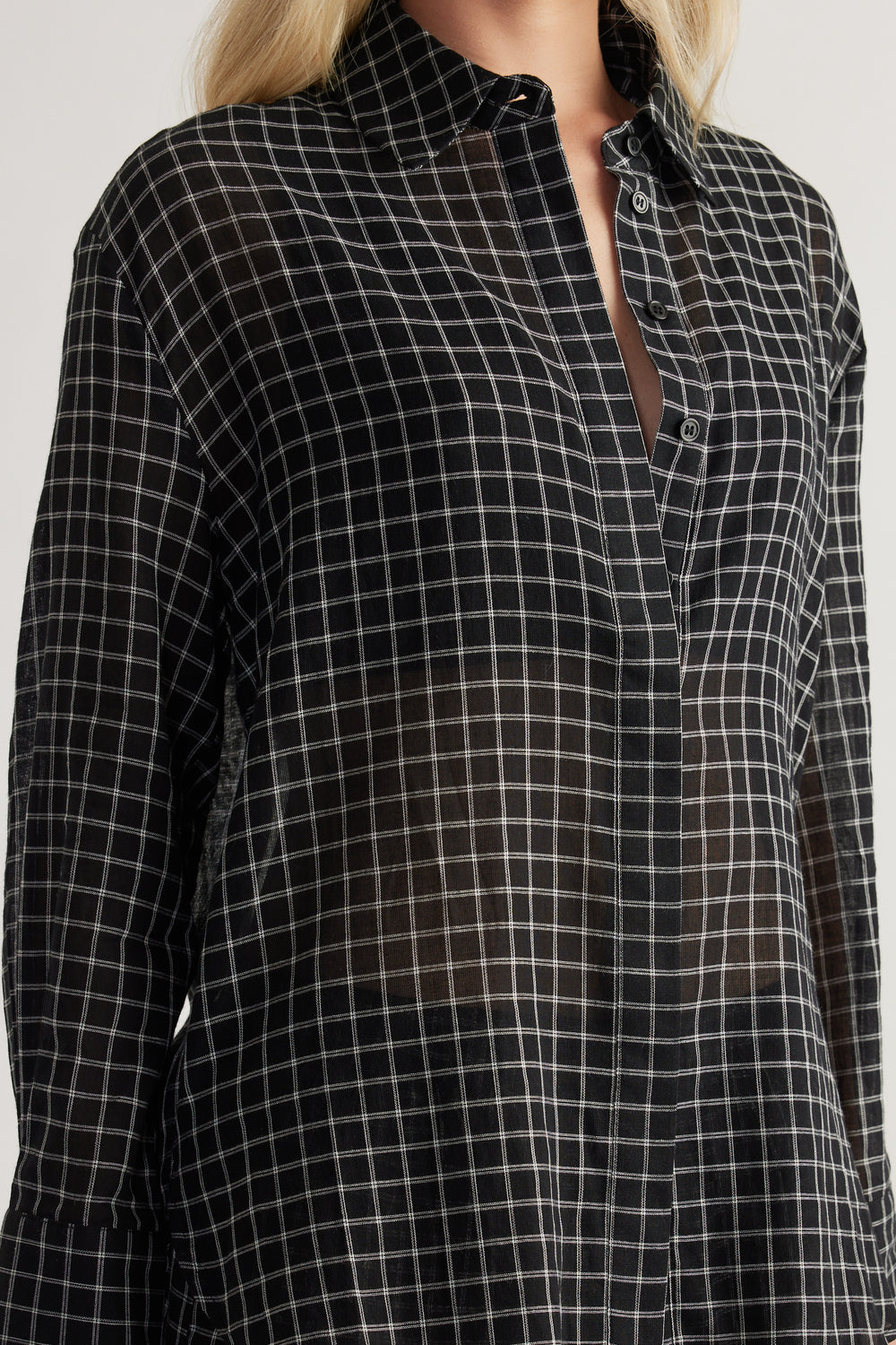Woman wearing a black check shirt with long sleeves a button front and an oversized fit