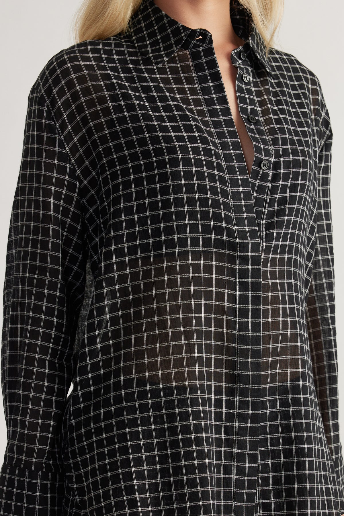 Woman wearing a black check shirt with long sleeves a button front and an oversized fit