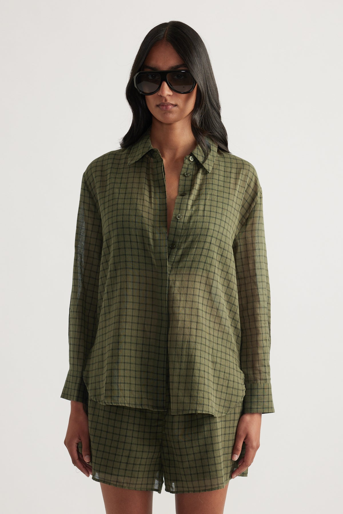 Model wearing an olive green checked oversized shirt with matching shorts