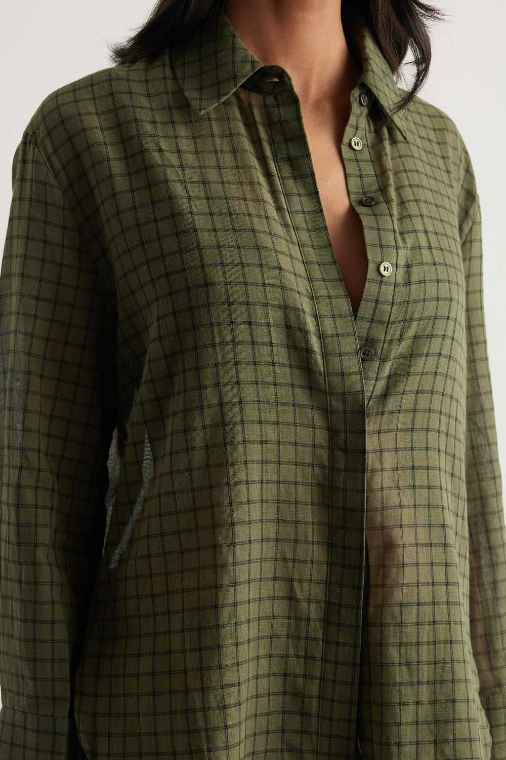 Woman wearing an oversized olive plaid shirt with a collared neckline and button front
