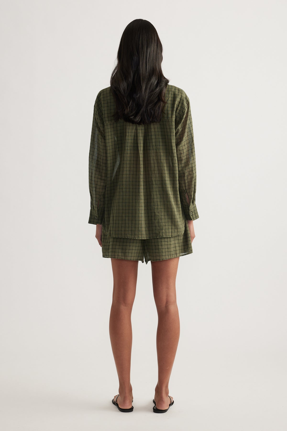 Back view of a model wearing an oversized olive check shirt with matching shorts