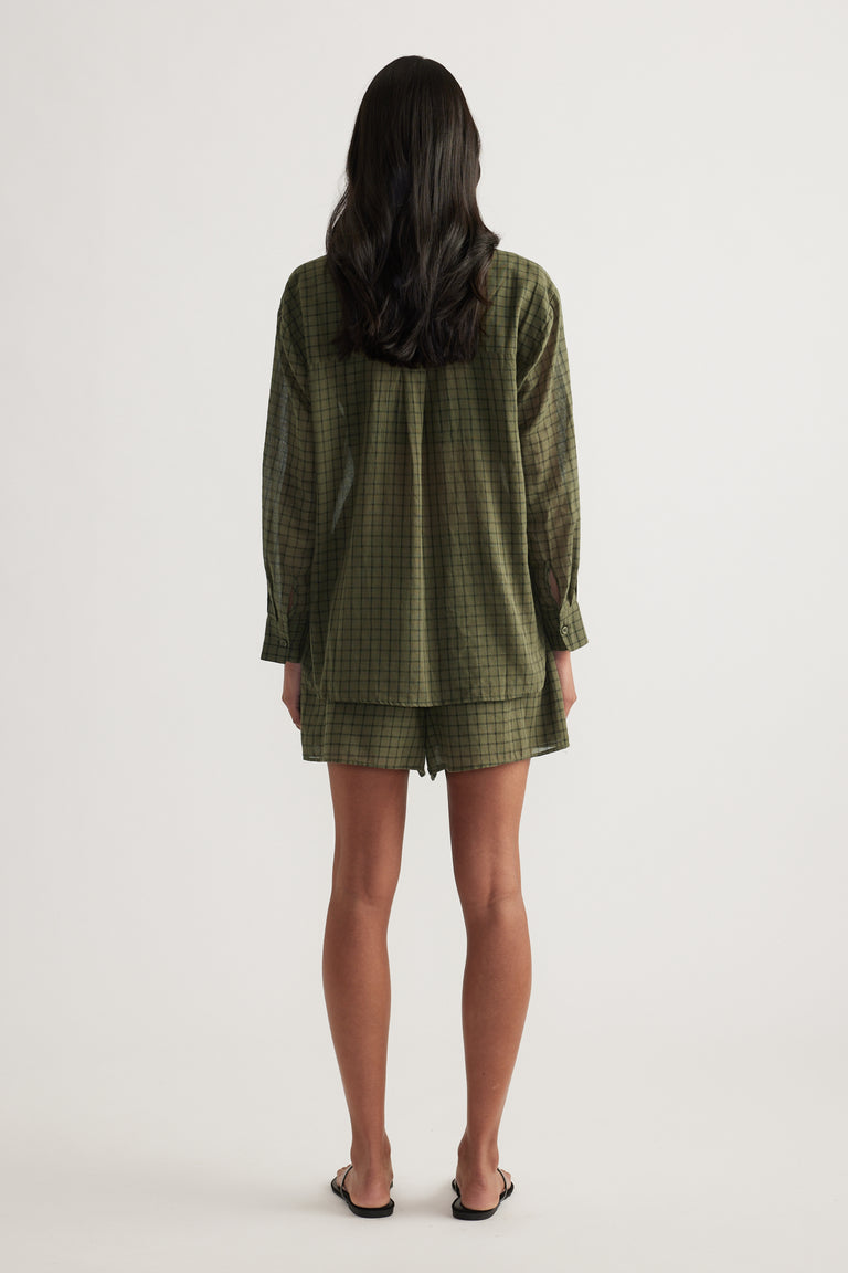 Back view of a model wearing an oversized olive check shirt with matching shorts