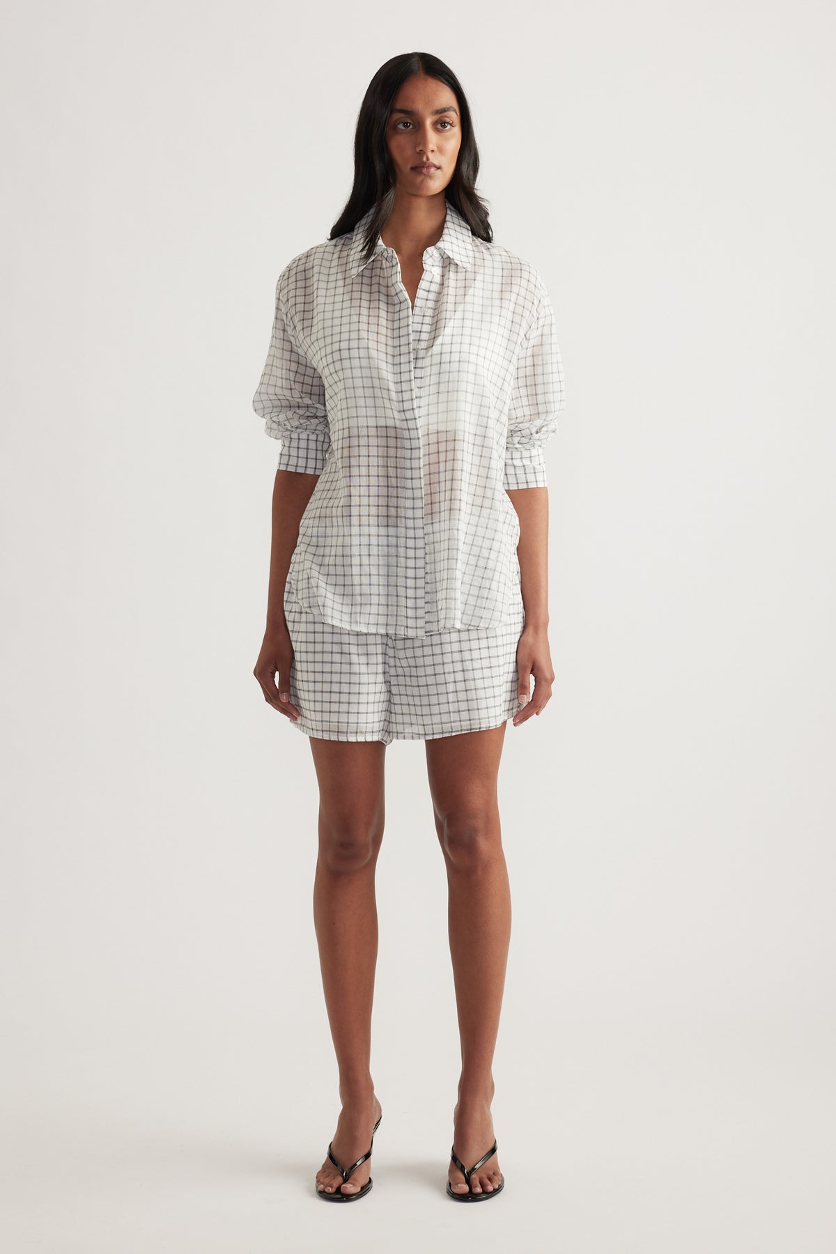 Model wearing an oversized checked button up shirt with matching shorts and sandals