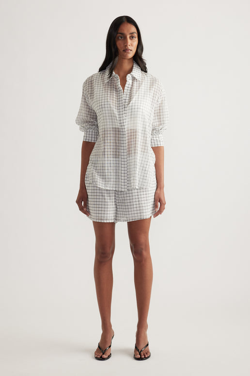 Model wearing an oversized checked button up shirt with matching shorts and sandals