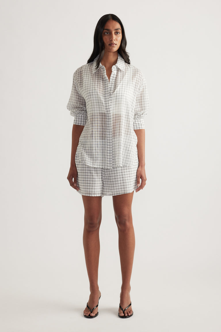 Model wearing an oversized checked button up shirt with matching shorts and sandals