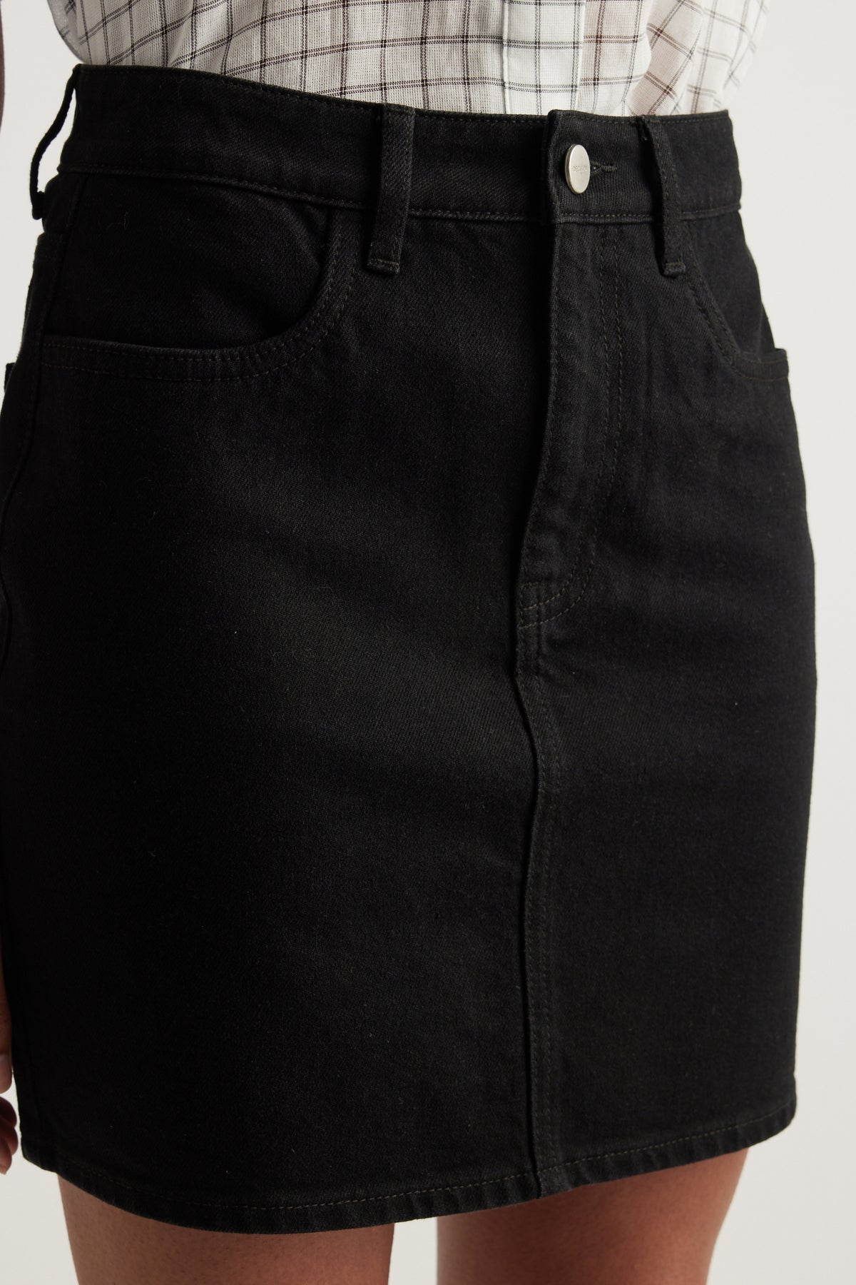 Black high rise denim mini skirt with front pockets, button fly and above the knee length